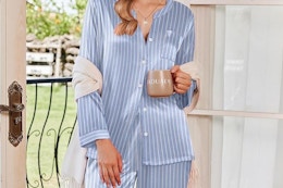 a woman holding a coffee while wearing pajamas