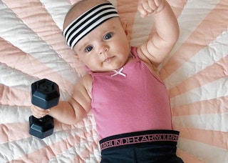 a baby with a dumbbell rattle 