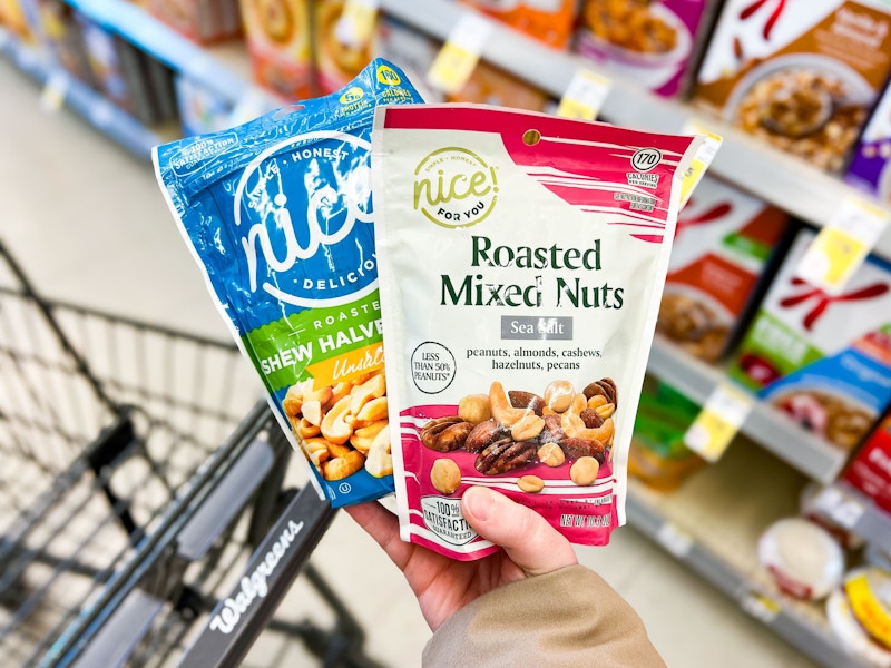 person holding bags of cashews and mixed nuts over a walgreens cart