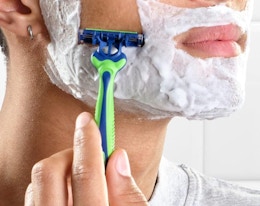 a person shaving their face with a razor