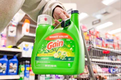 person holding a large jug of gain laundry detergent
