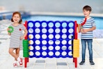Lifestyle image of 2 kids sanding next to a giant 4-in-a-row game by a pool