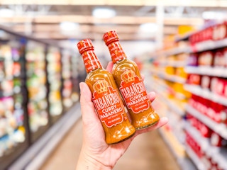 hand holding two bottles of tabanero hot sauce in walmart aisle