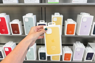 An iPhone case held out in front of a shelf full of other iPhone cases.