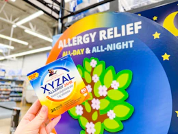 Xyzal product held up in front of allergy relief all day & all night sign in Walmart store