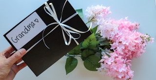 a person holding a gift box that says grandma on it