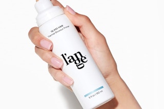 a hand holding a white pump bottle 