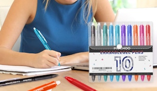 a person writing in a notebook with colorful pens at a table 