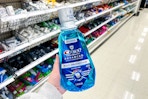person holding a bottle of crest mouthwash in an aisle