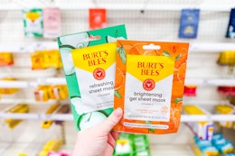 person holding 2 burt's bees sheet masks