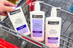 person placing neutrogena hair restore serum in a cart with shampoo and conditioner
