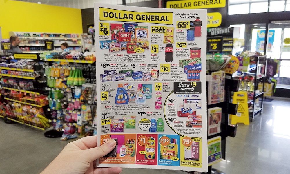 A hand holding up a Dollar General store ad inside the store.