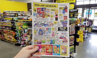 A hand holding up a Dollar General store ad inside the store.