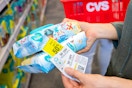 Woman holding coupons with two packs of pampers baby wipes in store.