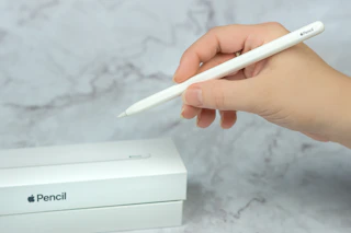 someone holding an apple pencil next to a box