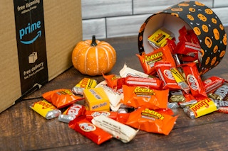 a halloween themed container spilling over with candy next to a pumpkin and amazon prime box