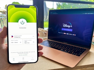phone with VPN app and laptop showing Disney Plus in background