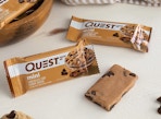 two packaged and one unpackaged protein bar on counter