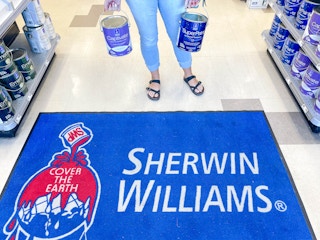 woman holding gallons of paint over a sherwin williams area rug