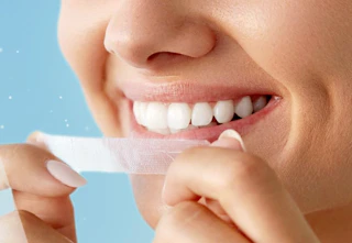 a person putting a whitening strip on their teeth