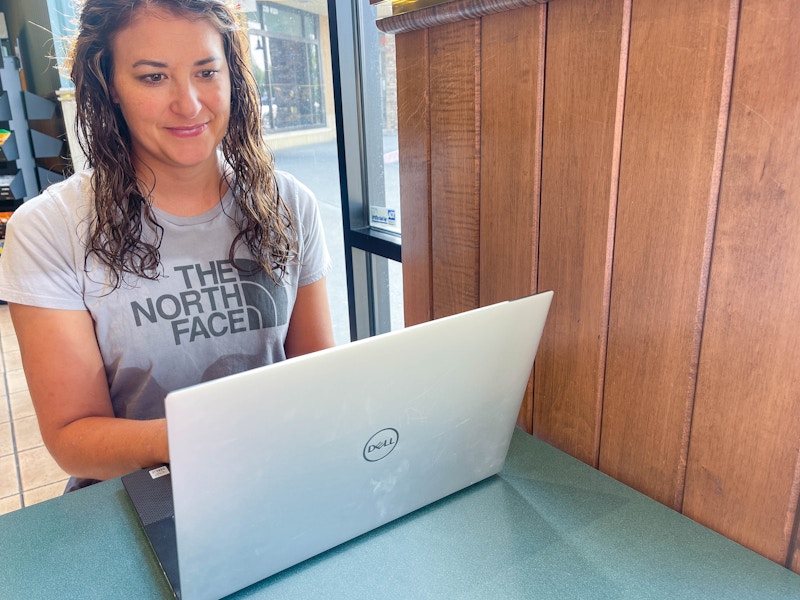 a woman on a laptop in cafe with a north face tee shirt on 