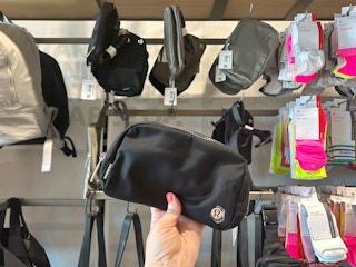 hand holding black lululemon belt bag in store