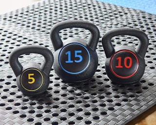 A set of three kettlebells on a gym floor.