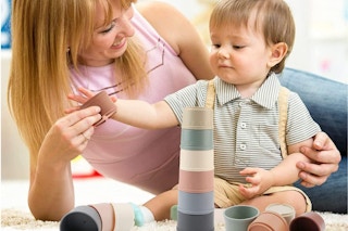 Adult and toddler playing together with stacking cups