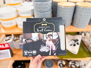 a hand holding up the Woof Hammock Seat Cover in store at kohl's