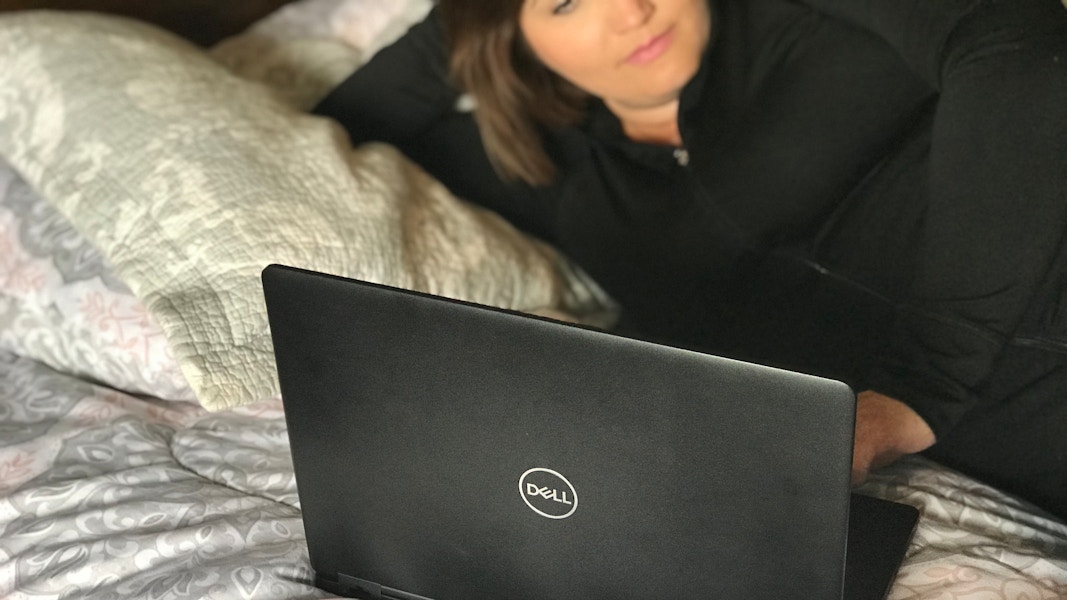 A woman laying on a bed looking at something on a laptop