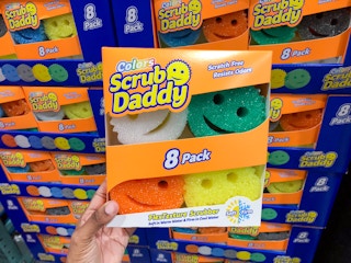 person holding an 8-pack of scrub daddy sponges in front of a display