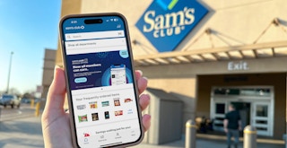 Someone holding up a phone displaying the Sam's Club app in front of a Sam's Club