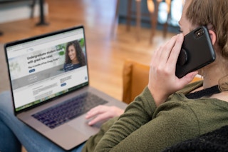 A woman on the phone with a computer open in front of her.