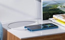 a phone charging on a counter with books 