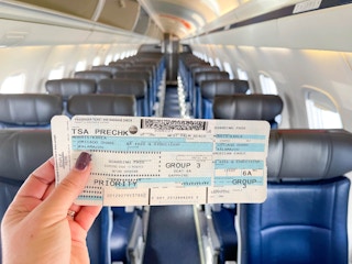 woman holding airplane ticket on empty plane