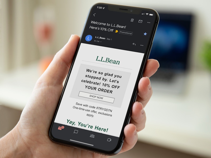 A person's hand holding a phone displaying the welcome email from L.L.Bean with a coupon