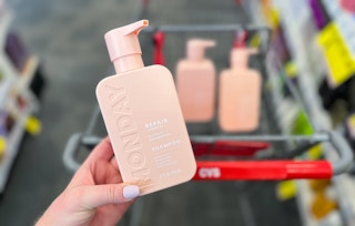 hand holding monday shampoo in front of cart