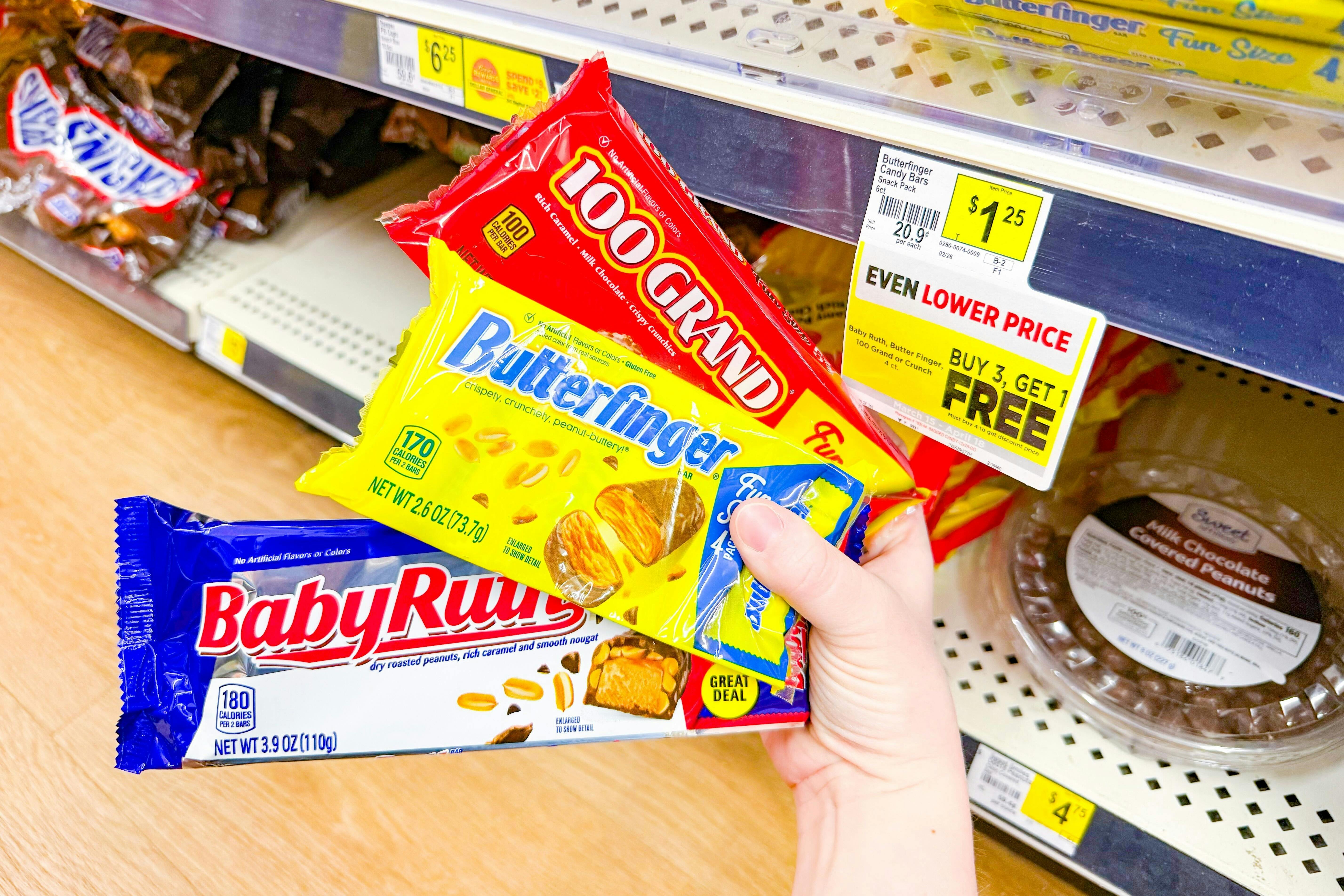 hand holding fun size packs of 100 grand, baby ruth, butterfinger