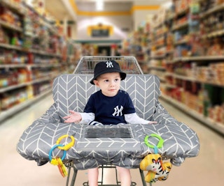 a baby sitting in a shopping cart cover at the store