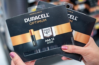 A person holding packages of Duracell Optimum batteries