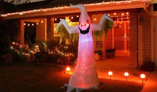 Red and white inflatable ghost in a yard with lights