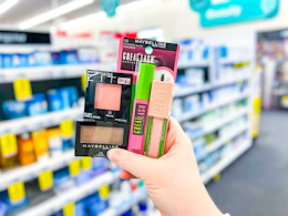 hand holding four maybelline cosmetics