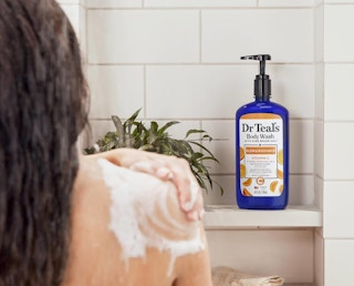 a blue pump bottle of body wash on a shower shelf