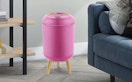 a pink trash can near a dark blue couch