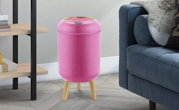 a pink trash can near a dark blue couch
