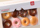 A box with a variety of different Krispy Kreme doughnuts inside.