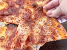 a close up of a person holding a pepperoni pizza