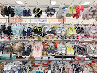 An area shot of a variety of toddler shoes hanging from a store rack.