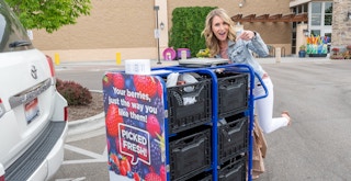 woman pushing a kroger grocery pickup cart to her trunk