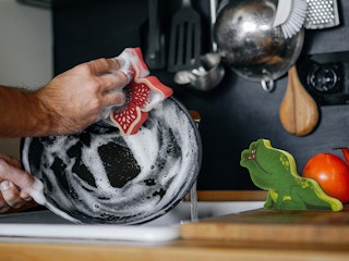 a person washing a dish with a Stranger Things sponge